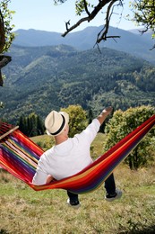 Man resting in hammock outdoors on sunny day, back view