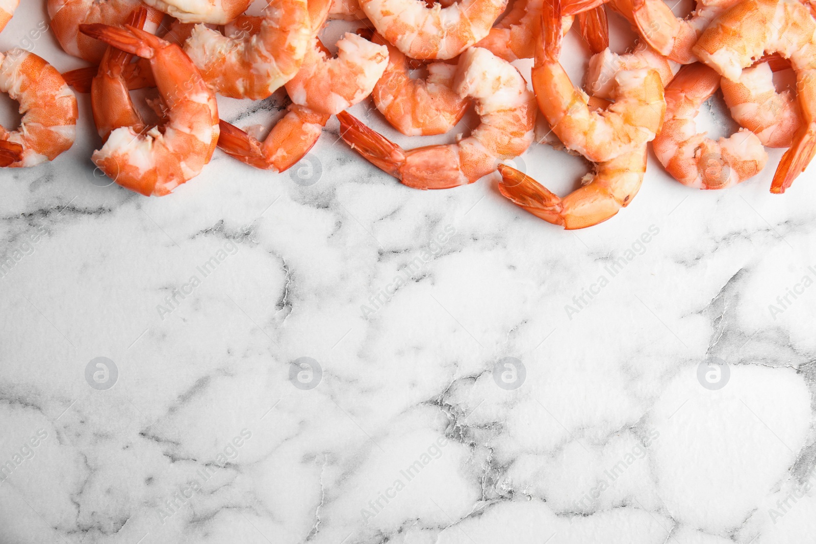 Photo of Tasty boiled shrimps on marble table, flat lay. Space for text