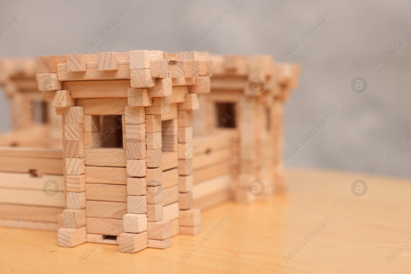 Photo of Children's toy. Wooden fortress on table against grey background, closeup. Space for text