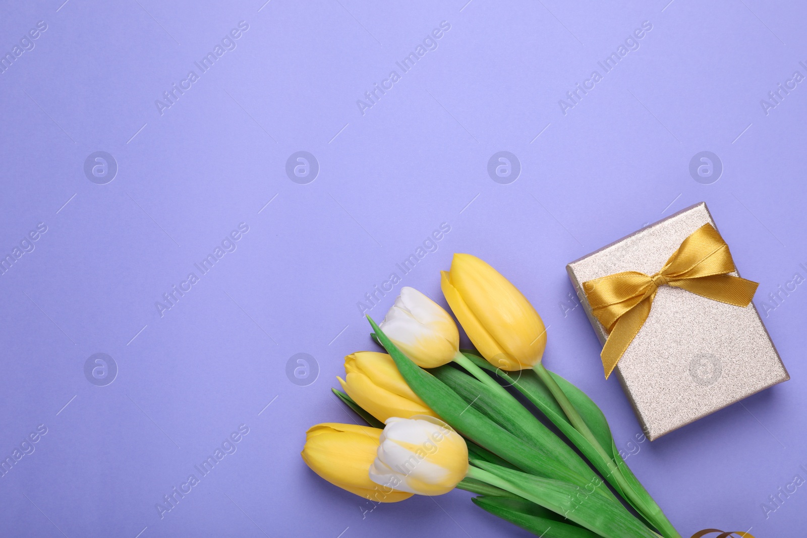 Photo of Bouquet of tulips and gift box on light purple background, flat lay. Space for text