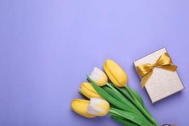 Photo of Bouquet of tulips and gift box on light purple background, flat lay. Space for text