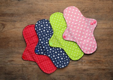 Many reusable cloth menstrual pads on wooden table, flat lay