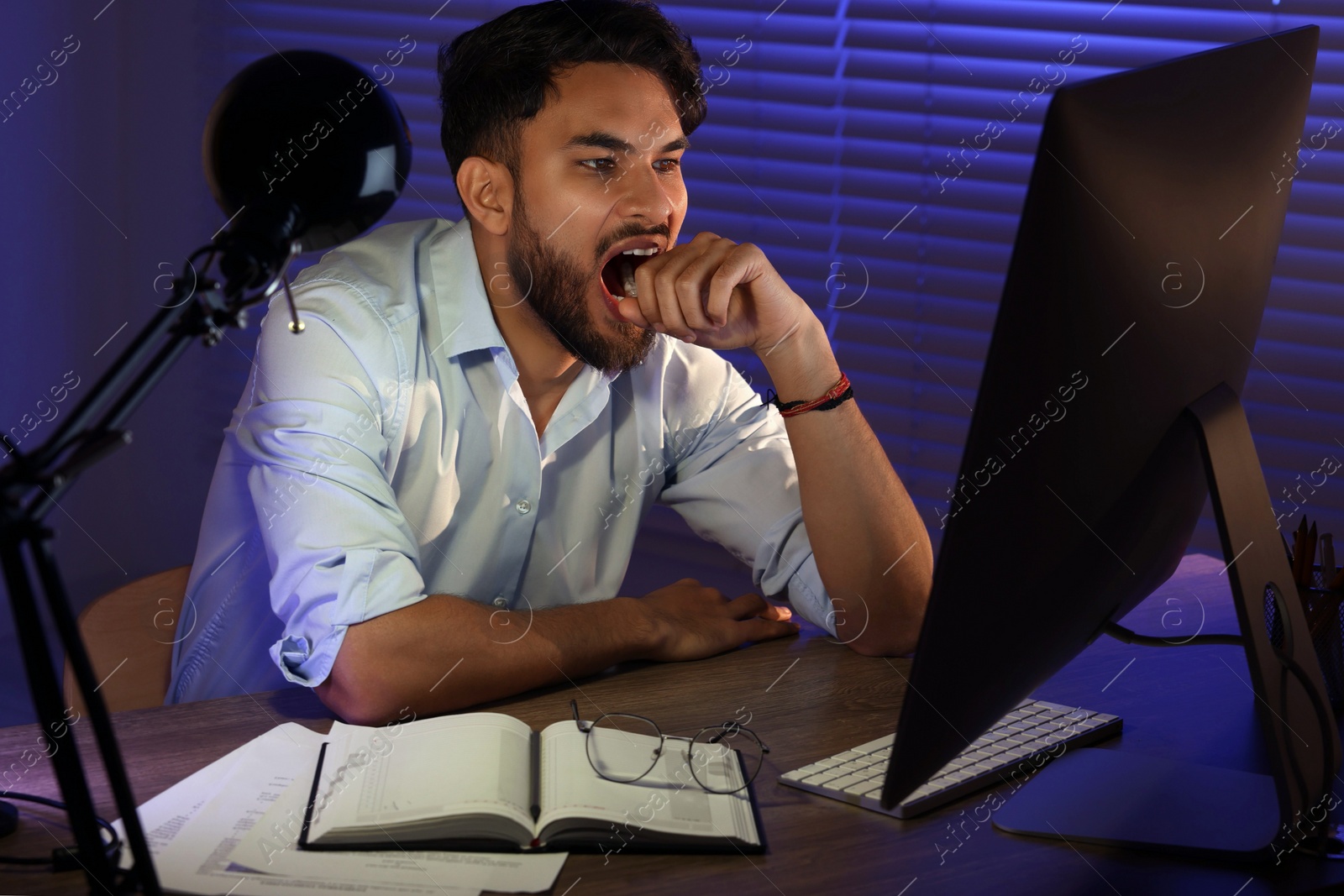 Photo of Tired young man working late in office