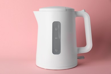 Photo of New modern electric kettle on pink background