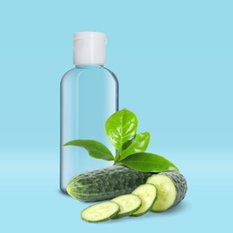 Image of Bottle of micellar cleansing water, fresh cucumbers and green leaves on blue background. Makeup remover