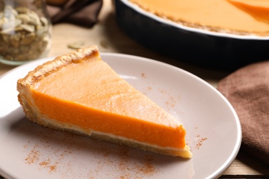 Plate with piece of fresh delicious homemade pumpkin pie on wooden table