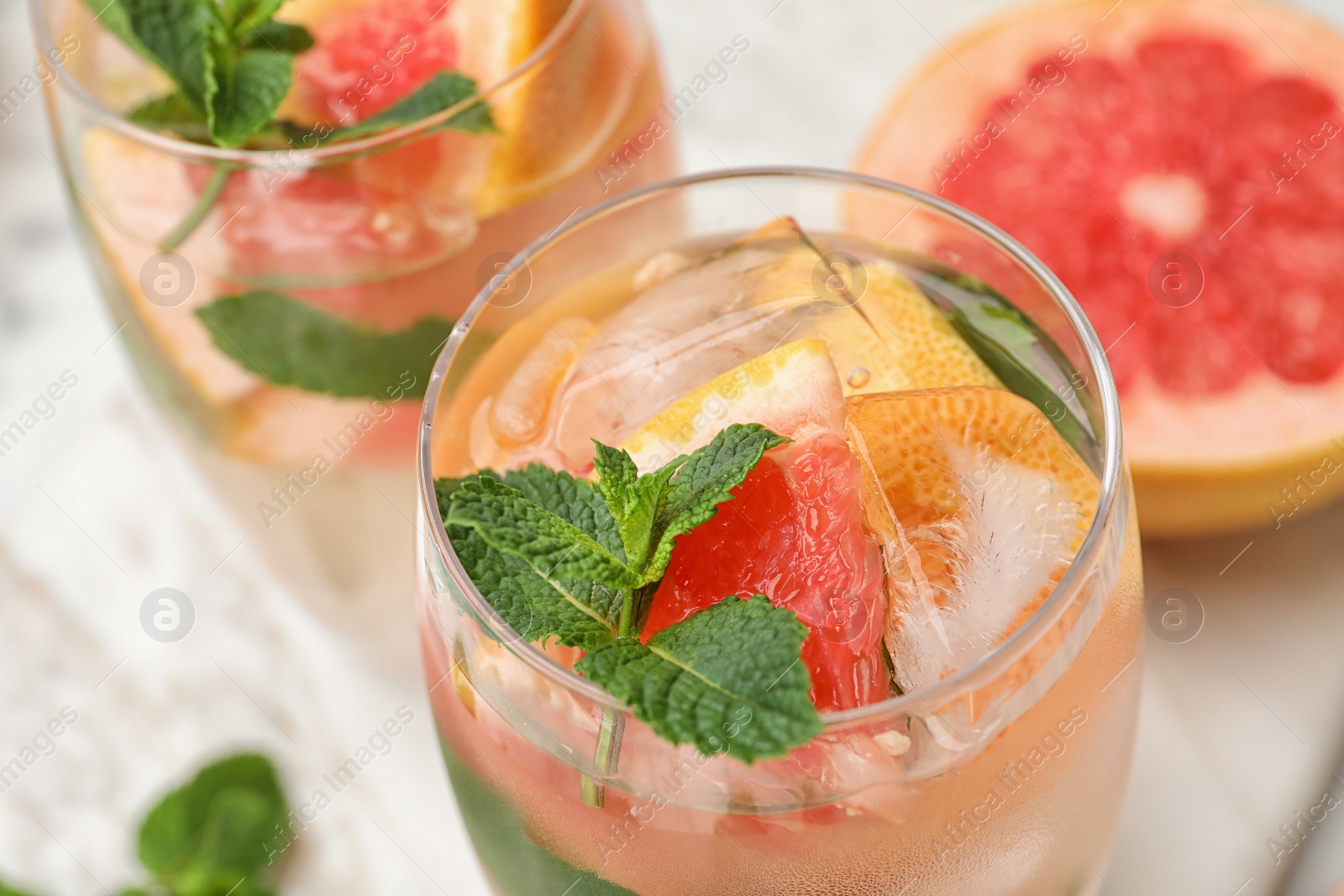 Photo of Glasses of refreshing drink with grapefruit and mint on table, closeup view