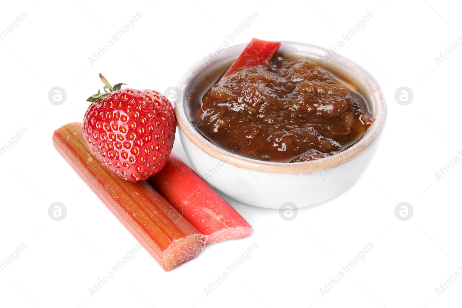 Photo of Tasty rhubarb jam in bowl, cut stems and strawberry on white background