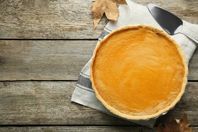 Photo of Delicious fresh pumpkin pie and server on wooden table, flat lay. Space for text