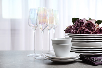 Photo of Set of glasses and dishes with flowers on light grey table