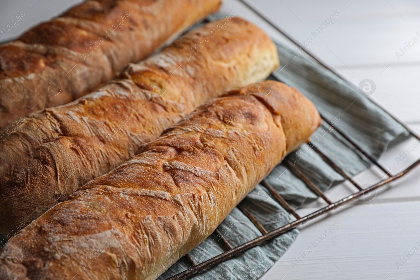 Photo of Fresh crispy ciabattas on white wooden table, closeup. Space for text