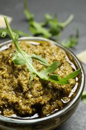 Photo of Bowl of tasty arugula pesto on table, closeup