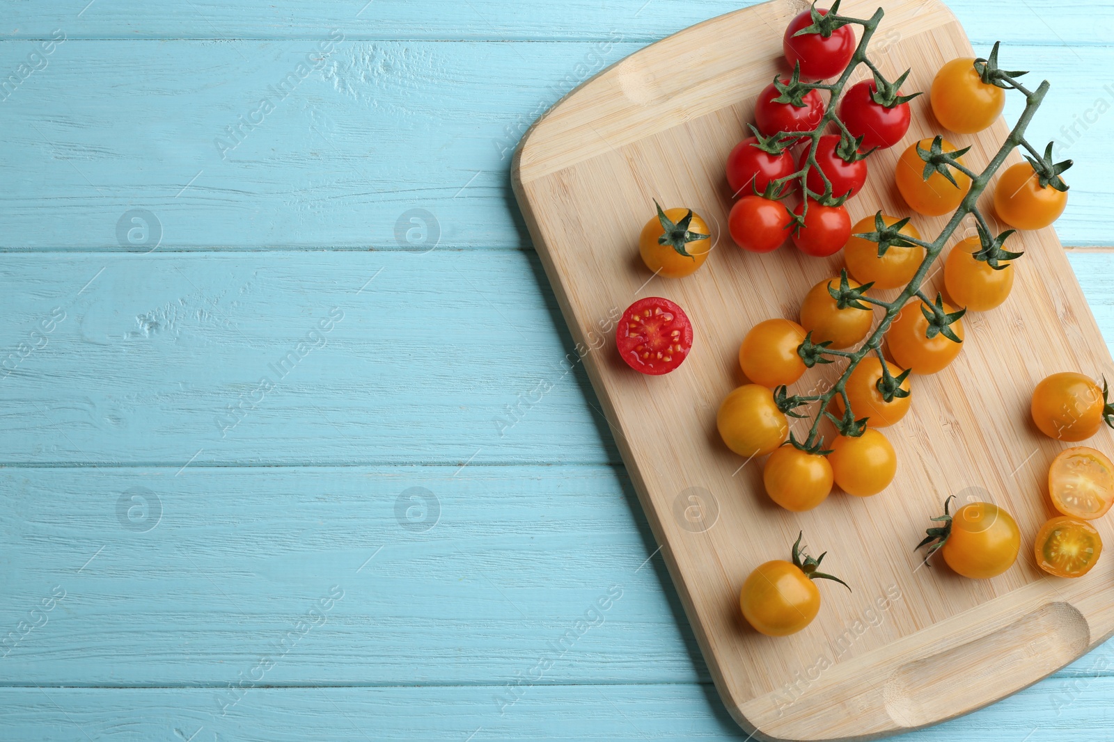 Photo of Ripe red and yellow tomatoes on light blue wooden table, top view. Space for text