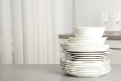 Photo of Stack of clean plates on grey table in kitchen. Space for text