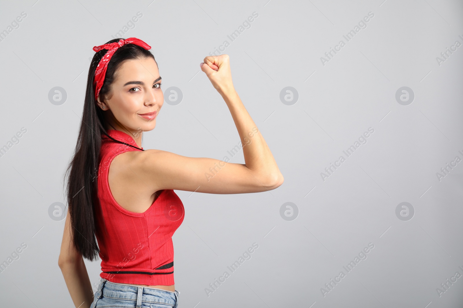 Photo of Strong woman as symbol of girl power on light grey background, space for text. 8 March concept