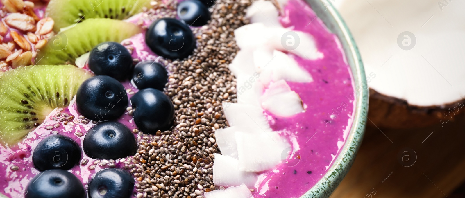 Photo of Delicious acai smoothie with fruits and chia seeds in bowl on table, closeup