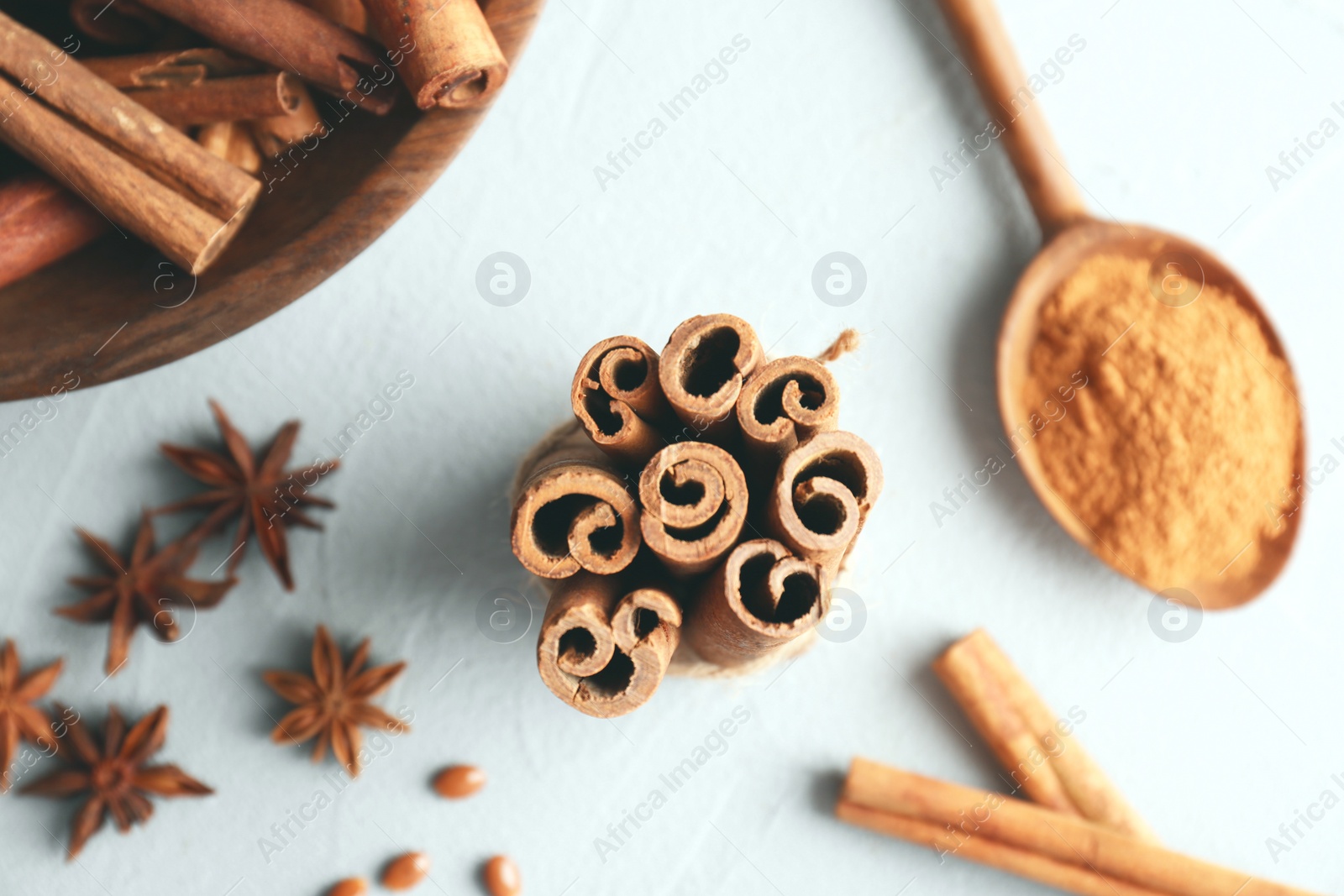 Photo of Tied cinnamon sticks and other spices on light background, closeup