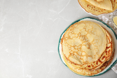 Photo of Stack of fresh thin pancakes on light grey marble table. Space for text