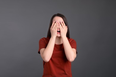 Emotional young woman on dark grey background. Personality concept