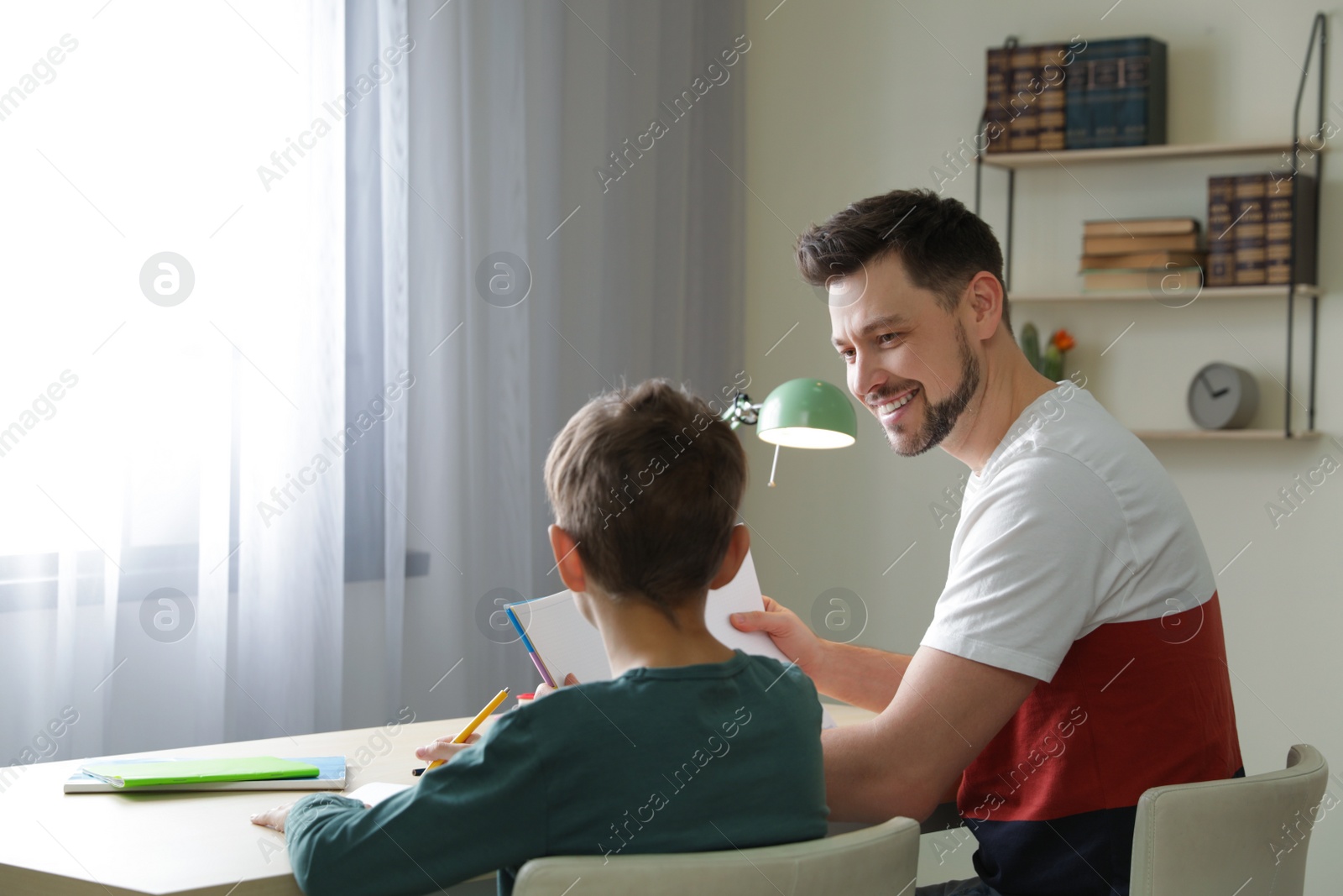 Photo of Dad helping his son with school assignment at home