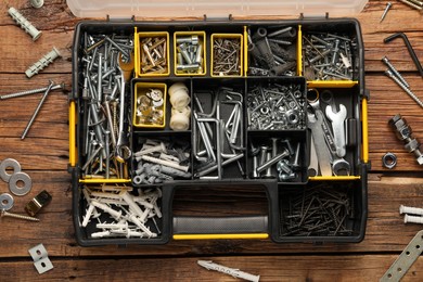 Organizer with many different fasteners and wrenches on wooden table, flat lay