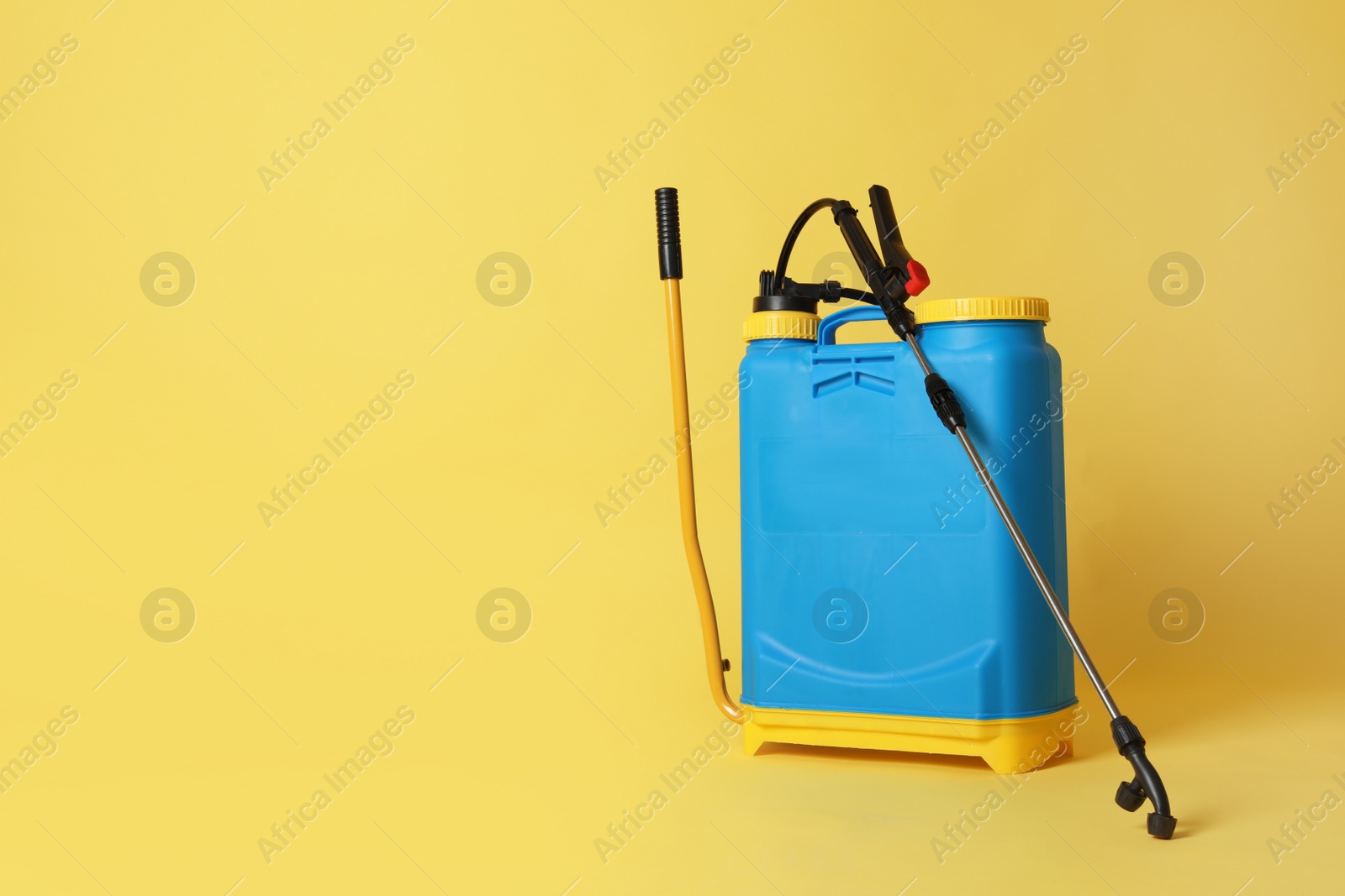 Photo of Manual insecticide sprayer on yellow background, space for text. Pest control