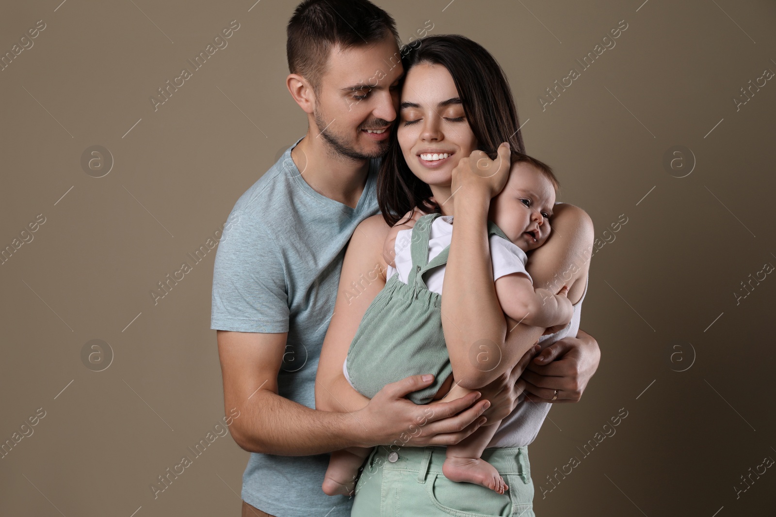 Photo of Happy family. Couple with their cute baby on beige background