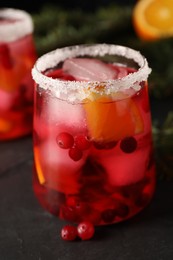 Tasty cranberry cocktail with ice cubes in glass on dark gray table, closeup