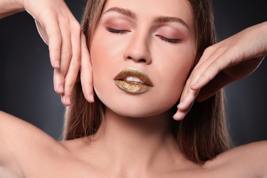 Woman with gold lipstick on grey background, closeup