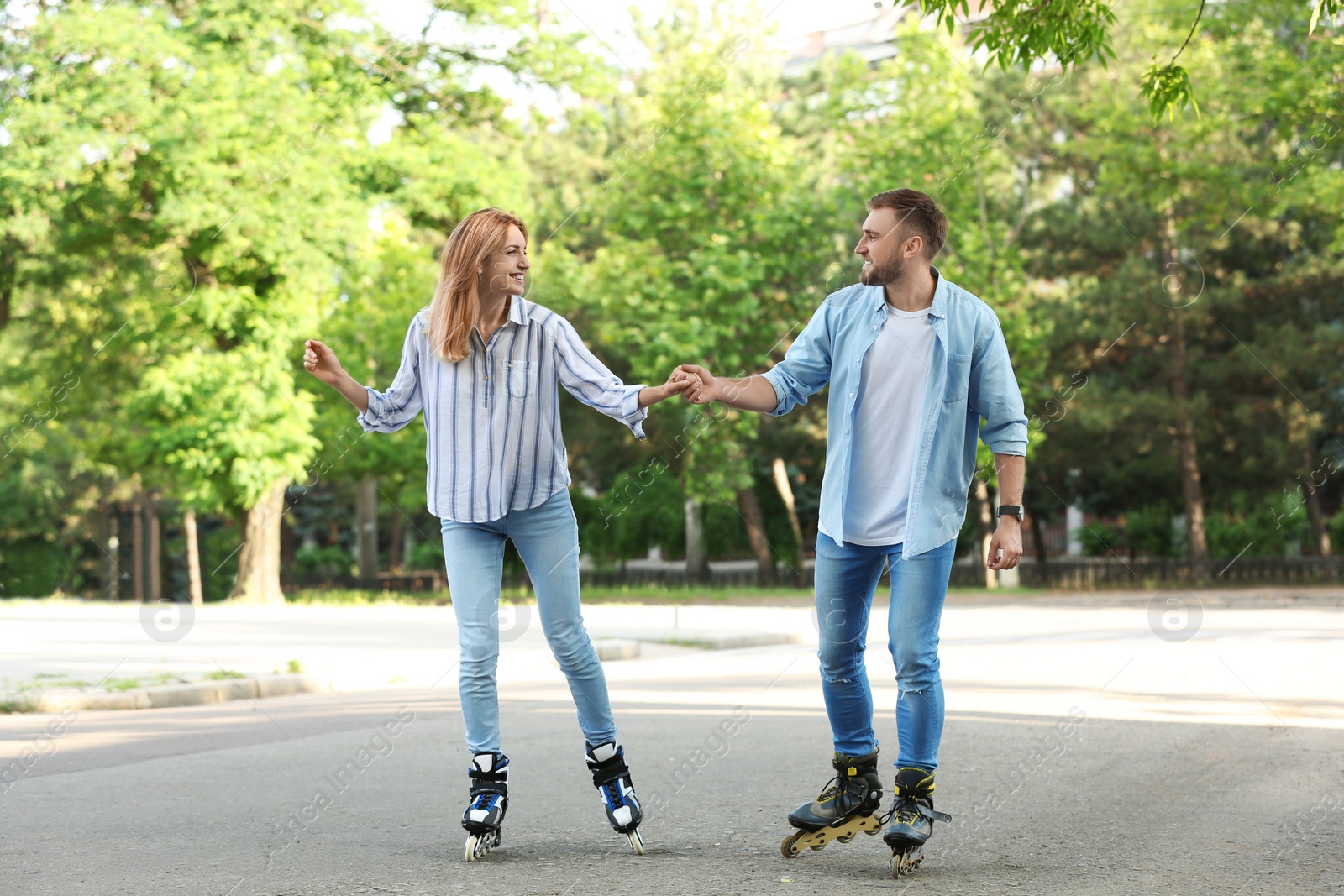 Photo of Young happy couple roller skating in summer park