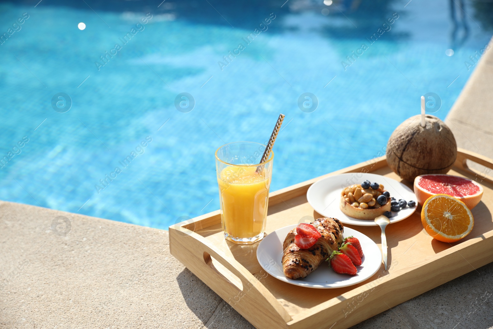 Photo of Tray with delicious breakfast near swimming pool. Space for text