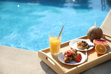 Tray with delicious breakfast near swimming pool. Space for text