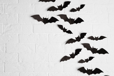 Paper bats on brick wall with space for text. Halloween decor