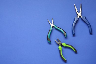 Different pliers on blue background, flat lay. Space for text