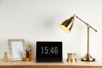 Photo of Modern workplace with laptop and golden decor on desk near wall. Stylish interior design