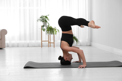 Professional young acrobat practicing yoga at home