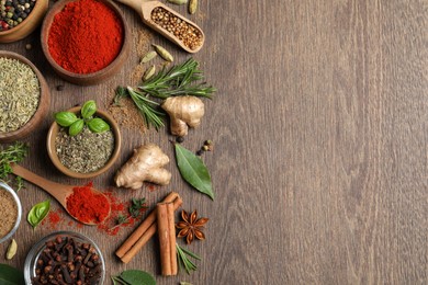 Different herbs and spices on wooden table, flat lay. Space for text