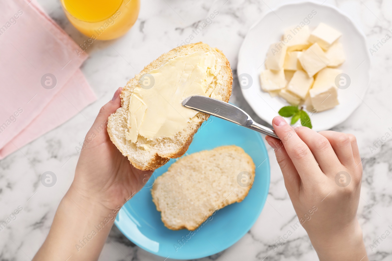 Photo of Woman spreading butter on slice of bread over table, closeup