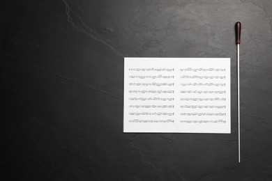 Conductor's baton and sheet music on black background, top view. Space for text