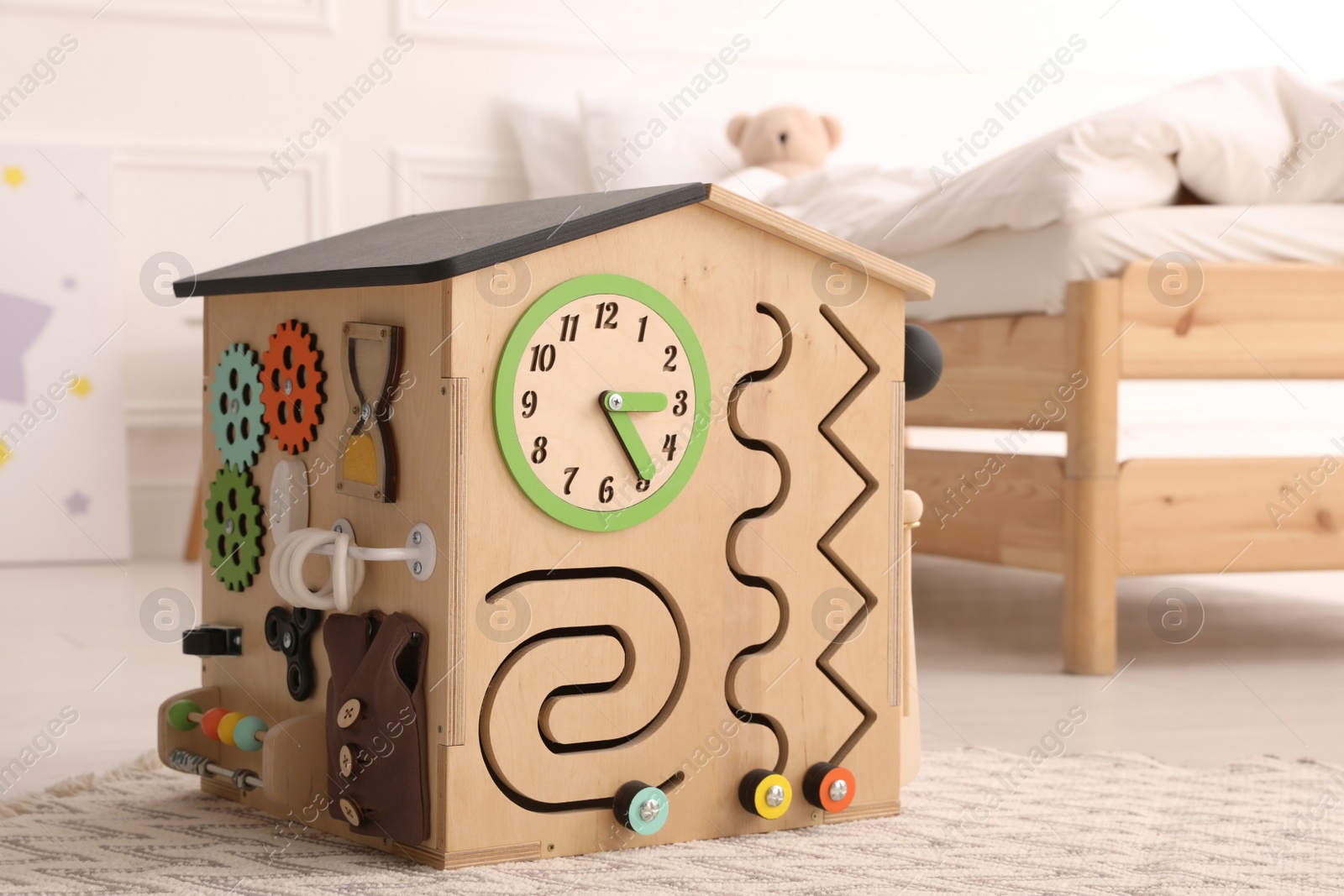 Photo of Busy board house on floor indoors. Baby sensory toy