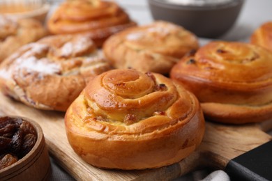 Delicious rolls with raisins and powdered sugar on table, closeup. Sweet buns