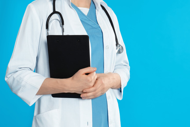 Photo of Doctor with stethoscope and clipboard on blue background, closeup