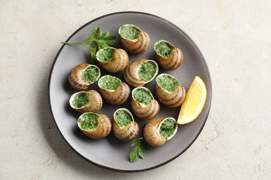 Photo of Delicious cooked snails with parsley and lemon on light table, top view