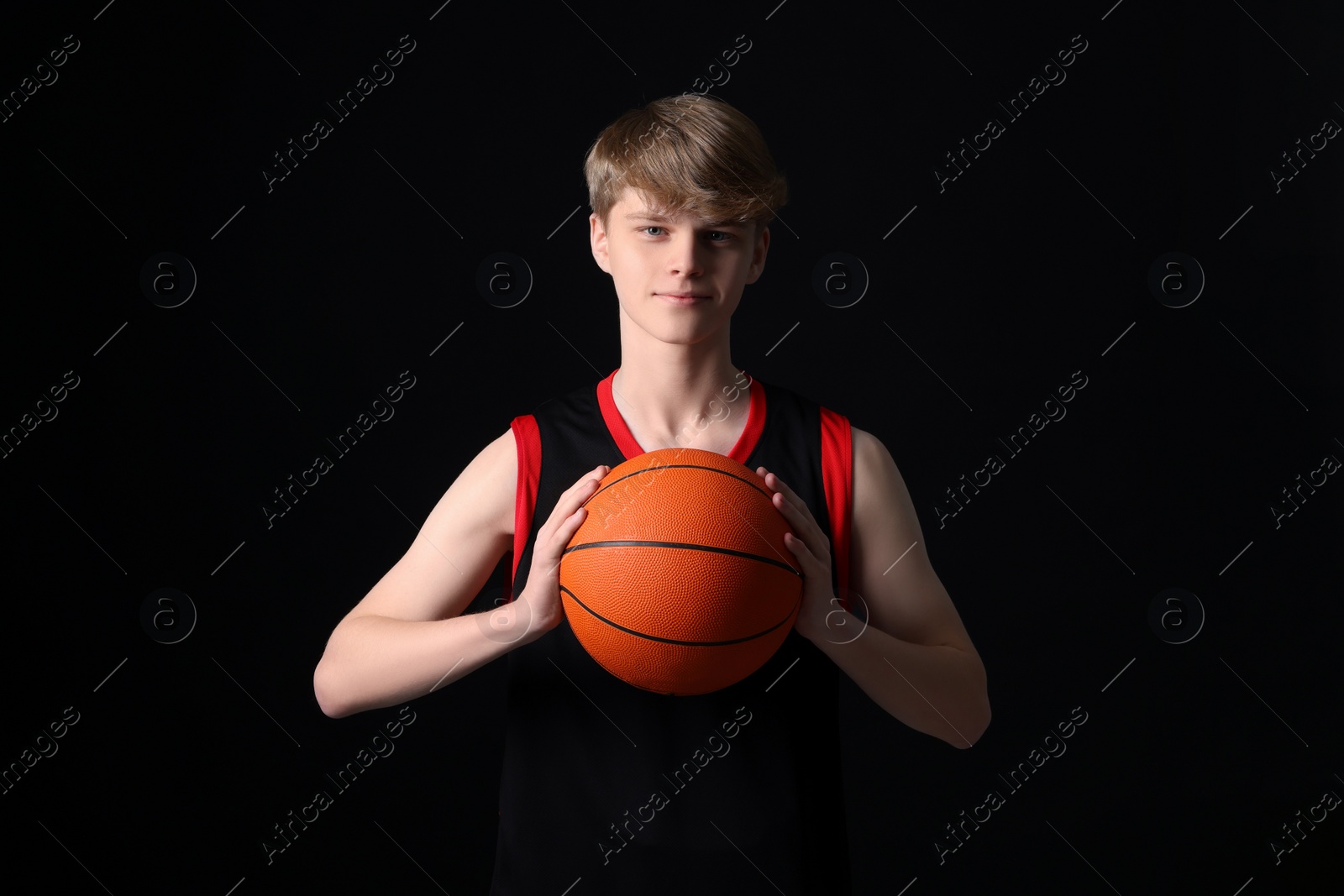 Photo of Teenage boy with basketball ball on black background