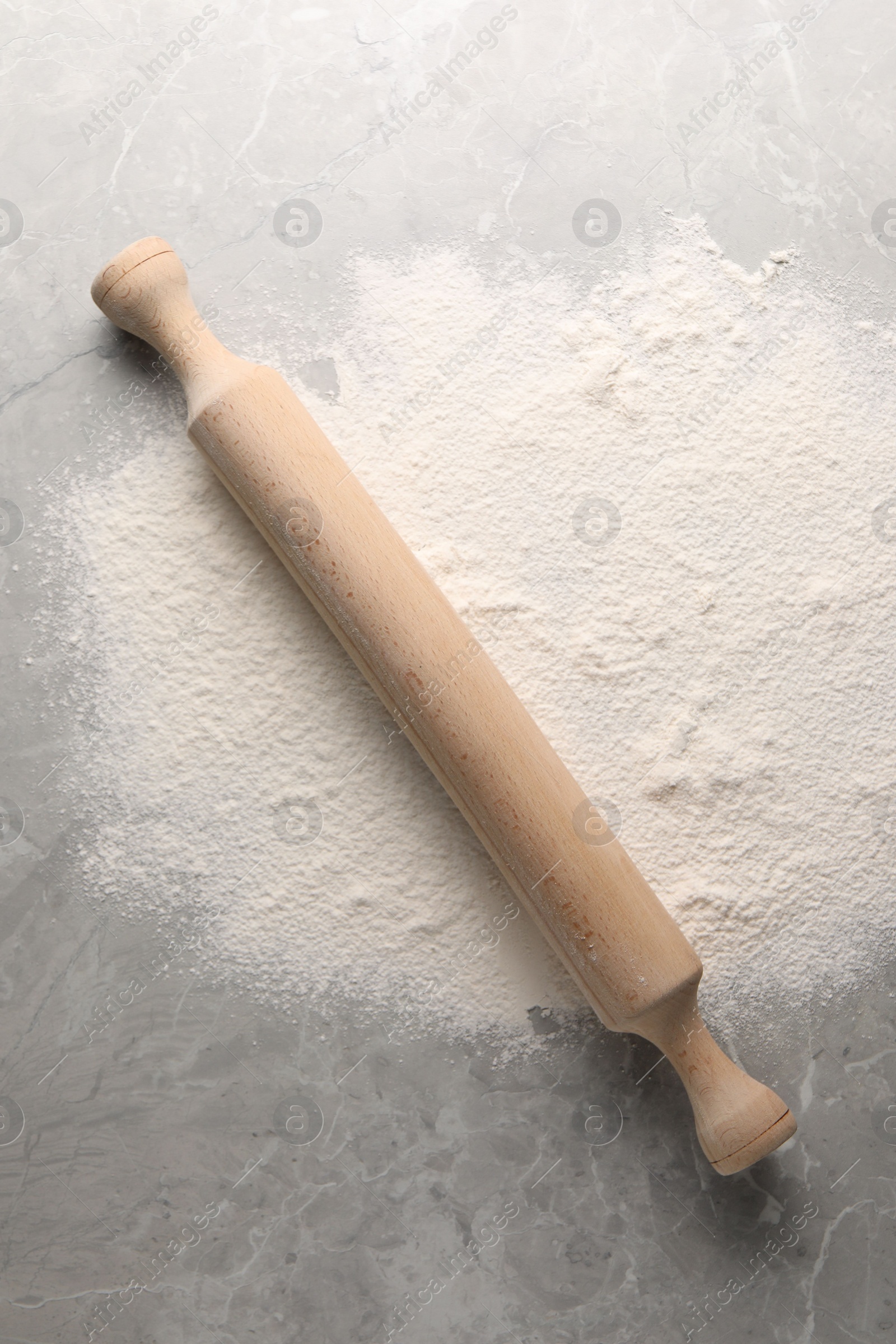 Photo of Pile of flour and rolling pin on grey marble table, top view