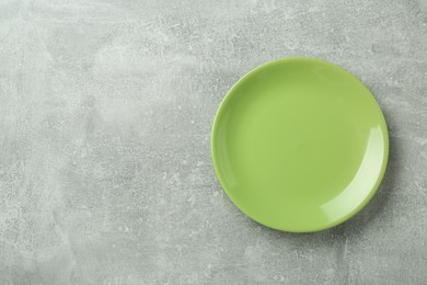 Photo of Clean green plate on grey table, top view. Space for text