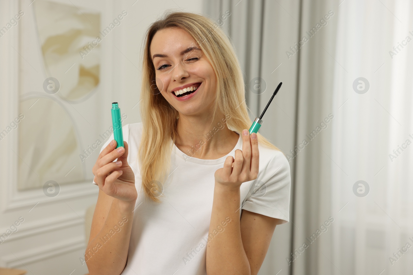 Photo of Beautiful happy woman with mascara at home