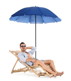 Young man on sun lounger under umbrella against white background. Beach accessories