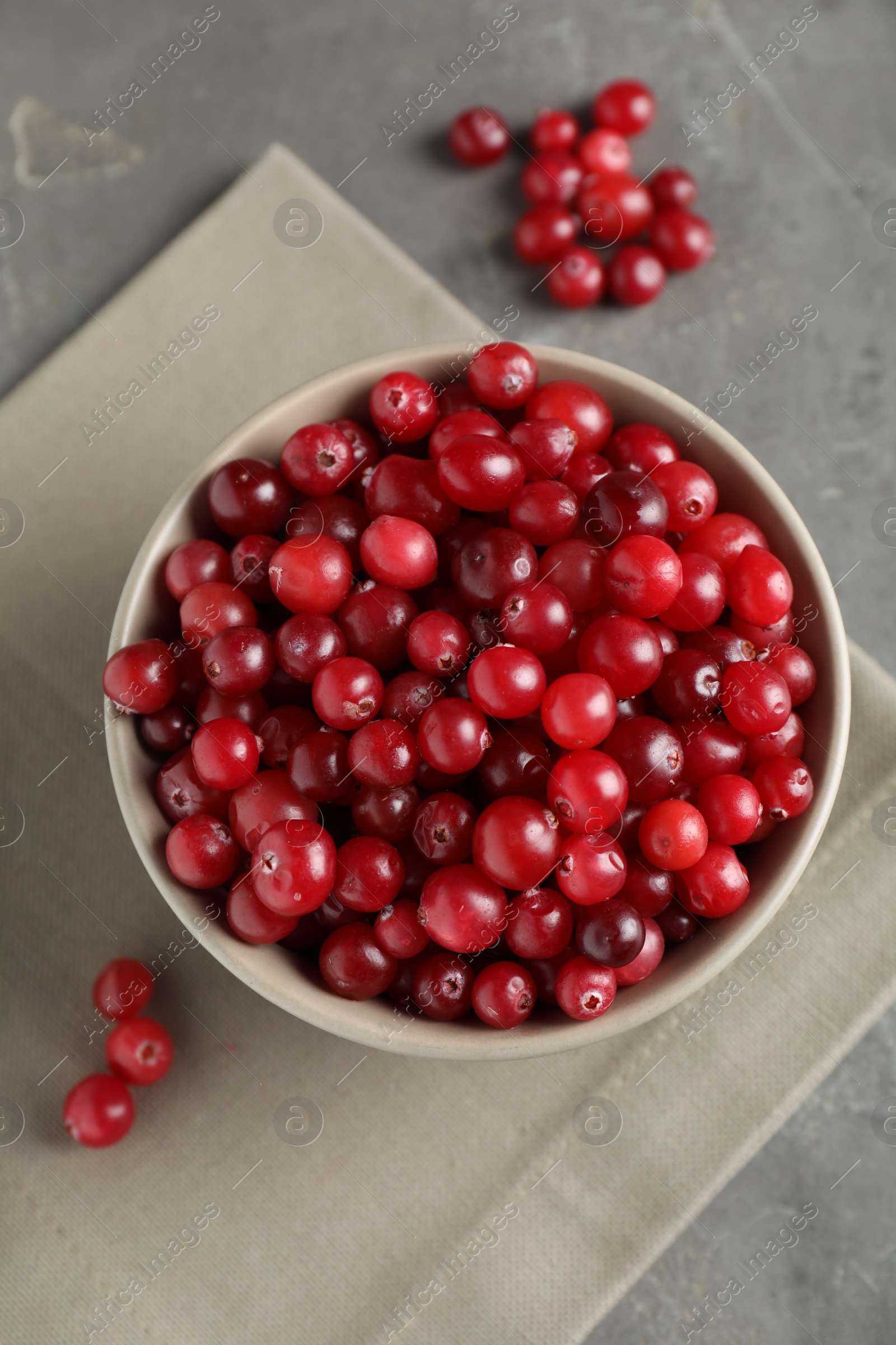 Photo of Cranberries in bowl on light grey table, top view