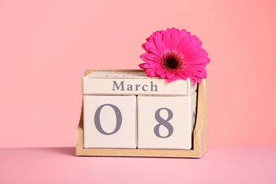 Photo of Calendar and flower on table against color background. International Women's Day